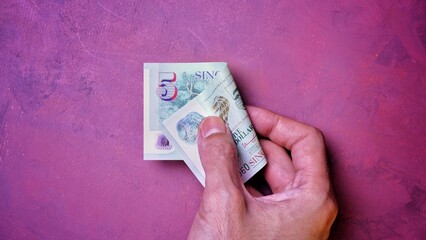 Businessman's hand holding Singapore Dollar Banknotes. Business Investment Economy Saving Loan Income Money and Finance concept. Prosperity concept. Five SGD . 5 SGD. Red Background.