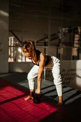 woman doing kettlebell snatch. girl in the back who is doing strength training. front view