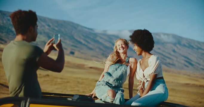 Diverse group of best friends laughing and taking pictures on epic summer road trip, travel and adventure lifestyle