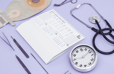 Clock with time seven, February 2022 calendar, surgical instruments, stethoscope and colostomy bag...