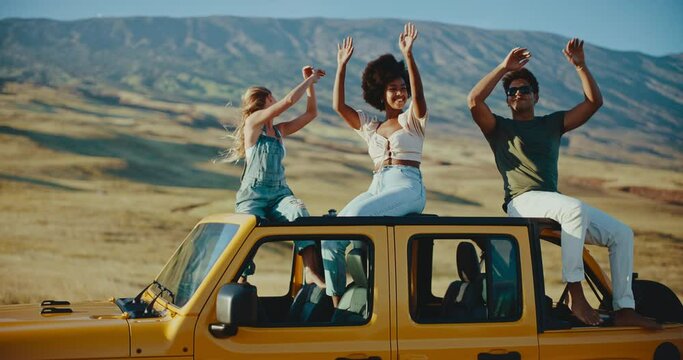 Diverse group of best friends dancing at sunset on epic summer road trip, travel and adventure lifestyle