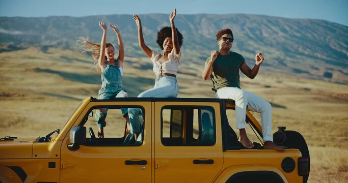 Diverse group of best friends dancing at sunset on epic summer road trip, travel and adventure lifestyle