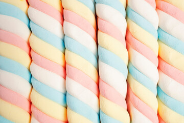 Marshmallow in twisted pattern, Pastel colored sweet chewy candies background.
