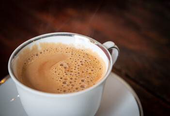 Close up of a cup of Masala tea on wooden table. Masala tea is a mixture of many ingredients including ginger, cardamom, cinnamon, cloves, and black pepper.
