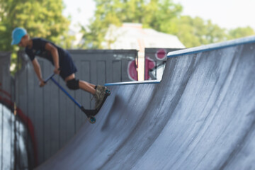 Skate park view with kids on a kick scooter doing tricks and stunts, boys in a skate park riding...