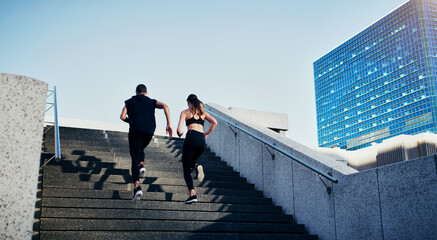 Do whatever gets your blood flowing. Rearview shot of a young man and woman running up stairs together in the city.
