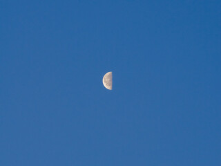 half face of the moon with clear blue sky