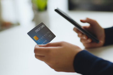 close up hand using phone and credit card for shopping online or credit payment
