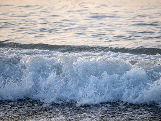 Sea waves at sunrise with black sand