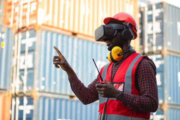 African-American male engineers wearing VR Headset look container cargo ship.