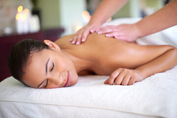 Fototapeta na wymiar Fall into a relaxed, rejuvenated new you. Shot of a young woman enjoying a back massage at a spa.