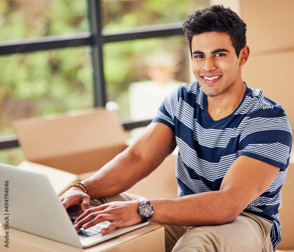 Poster just moved in and already connected. portrait of a young man using a laptop while taking a break fro