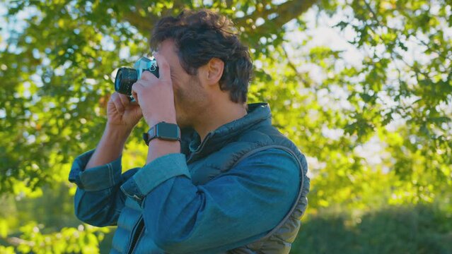 Mature man taking and reviewing picture in autumn countryside on retro style digital camera - shot in slow motion