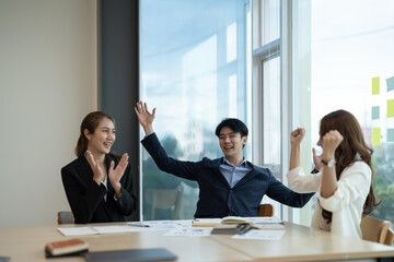 Euphoric excited young asian business team celebrate corporate victory together in office.