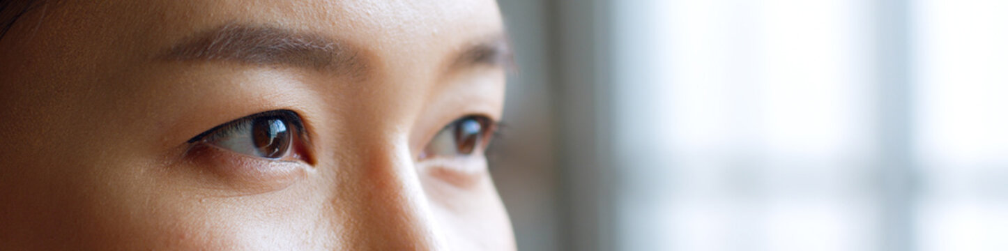 Close up of young asian woman eyes with copy space for banner. Look out to window
