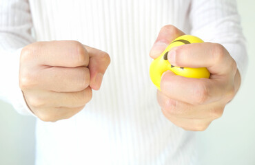 Hands of man with a gentle personality He exhibits stressful behavior from work, and he squeezes the yellow ball expressing emotion, anger, displeasure. Medical concepts and emotional regulation