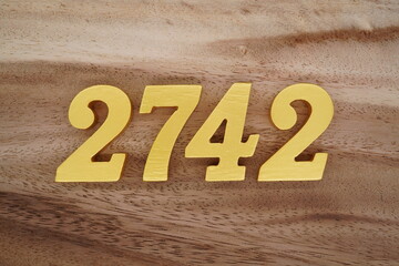 Golden Arabic numerals on a real brown and white wooden floor number 2742