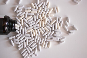 Vidro e cápsulas de medicamentos , sobre mesa branca.