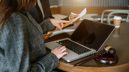 Business and lawyers discussing contract papers with brass scale on desk in office.