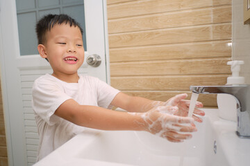 Handwashing, Cute little Asian 5 years old kindergarten boy child washing hands by himself on sink and water drop from faucet in toilet, Hygiene Habits for Kids concept, Soft and selective focus