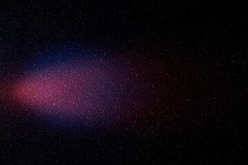 On a black background with multi-colored grain, a red and blue gradient beam of light