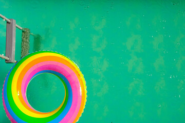 Obraz premium Rainbow swim ring in the pool.Summer time. Swimming ring in the pool in blue water on a summer day . Bathing season.View from above.S Summer weather