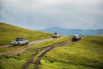 cars is moving along a dirt road. travel by car in the mountains. rough road in the steppe. jeeps make their way through the desert © denis