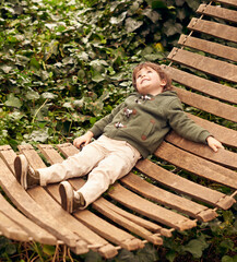 Daydream the day away. A little boy relaxing in a hammock in his backyard.
