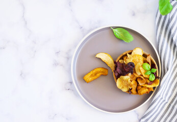 Vegan snacks, multicolored vegetable and fruits chips in wooden bowl , selective focus. Bowl of healthy vegetable chips from beets, sweet potatoes,apples, oranges and carrots.