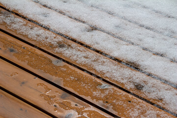 Abstract texture background of melting snow on a hardwood cedar deck in springtime
