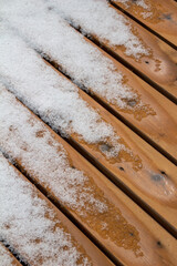 Abstract texture background of melting snow on a hardwood cedar deck in springtime