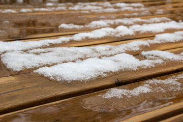 Abstract texture background of melting snow on a hardwood cedar deck in springtime