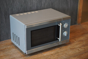 old grey and silver microwave oven on wooden floor background, decor, technology, fashion, copy...