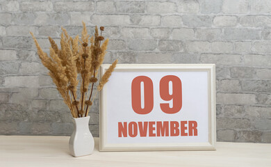 november 9. 9th day of month, calendar date.  White vase with ikebana and photo frame with numbers...