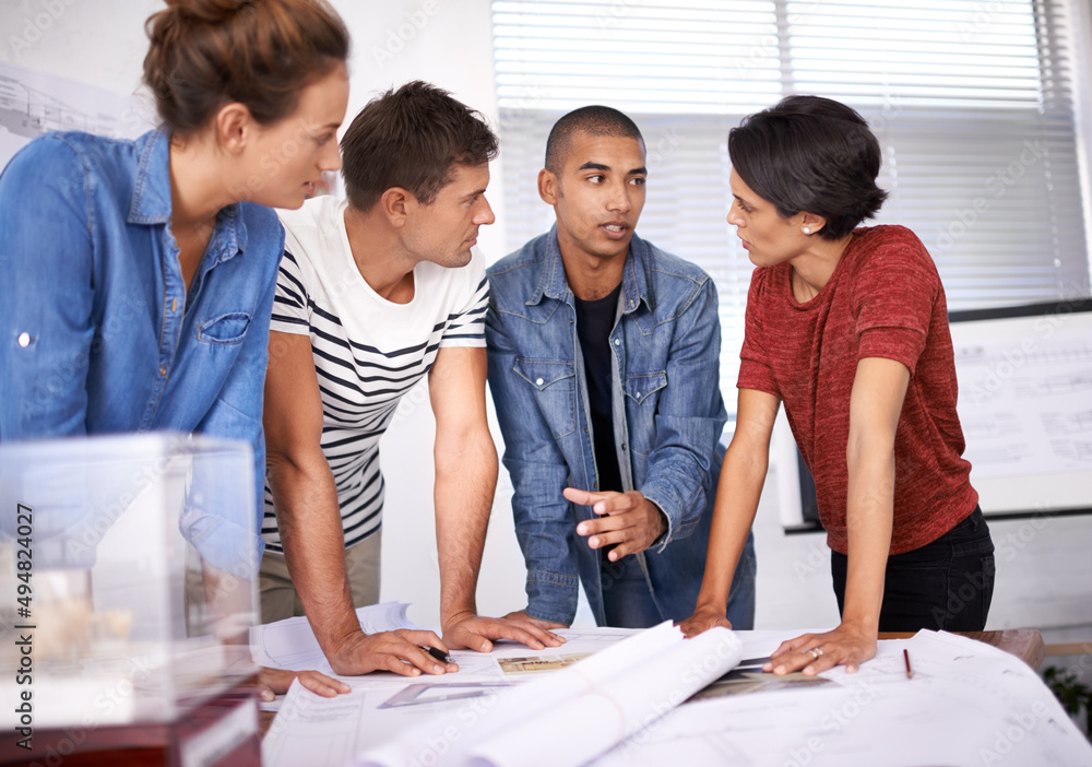 Poster explaining his design concept. shot of a group of young designers working together in an office.