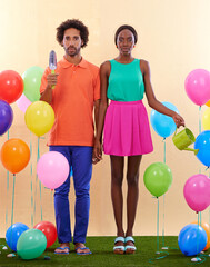 Fototapeta na wymiar Feeling a bit out of place.... An awkward african couple surround by colorful balloons while holding hands.