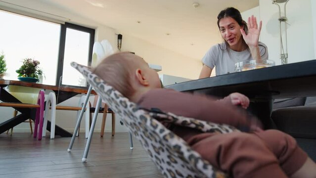 Baby in a crib and mom make eye contact and gesturing