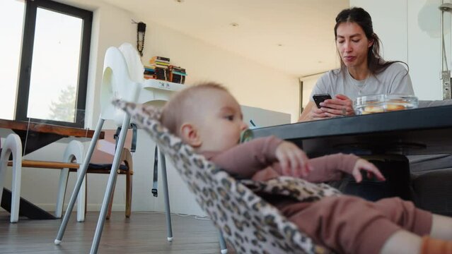 Baby with pacifier in crib mom babysitting and texting