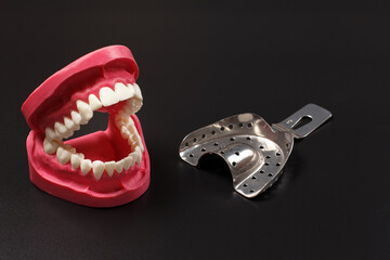 Stainless steel dental tols and layout of a human jaw on the black background.