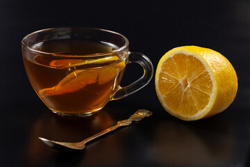 Cup of tea and pieces of lemon on black background