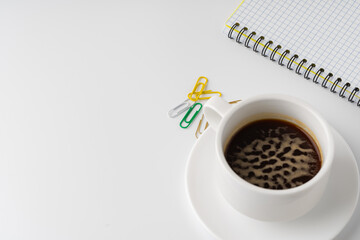 Cup of coffee and notepad on white background