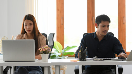 Female and male worker are works on their laptop computer