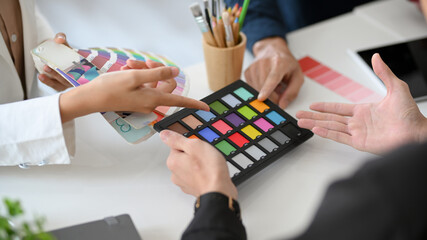 Group of graphic designers pointing their fingers on colour swatches samples