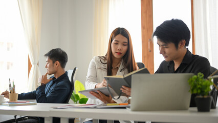 Fototapeta premium Female employee working and planning project with male colleague