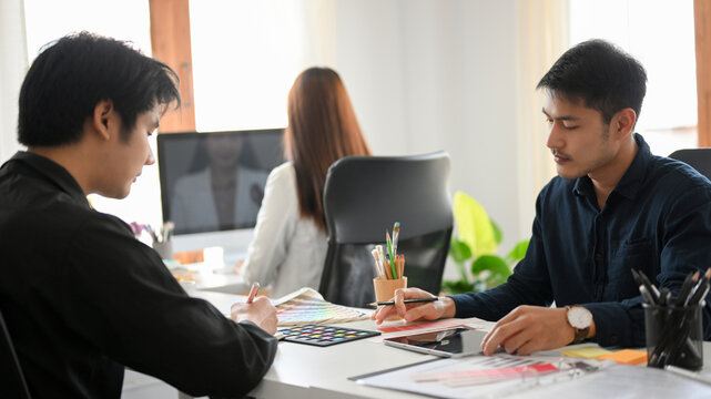 Two Asian male graphic designers are brainstorming and working together
