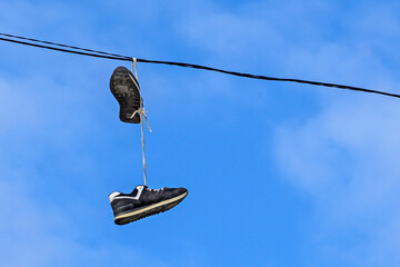 A pair of old sneakers hanging on an electric wire