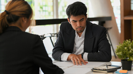 Stressed Asian male executive manager reading the informations on paperwork