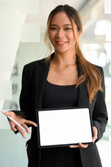 Businesswoman in black suit holding tablet, showing white screen tablet
