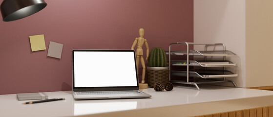 Trendy modern workspace interior with portable laptop against pink wall.