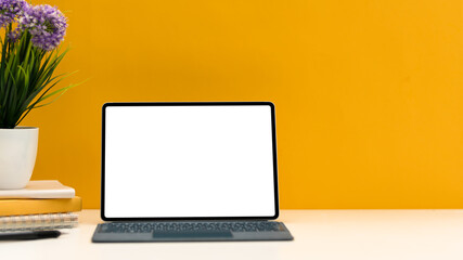 Creative stylish workspace with portable tablet mockup over yellow background